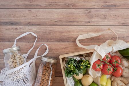 Cotton eco net bag with fresh vegetables in the pine wood box and sustainable glass jar on wooden table flat lay.plastic free for groceries product shopping and delivery. zero waste lifestyle .の素材 [FY310147545745]