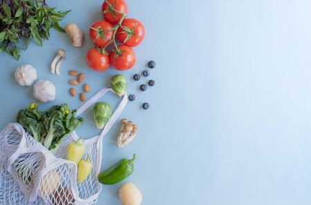 Cotton eco net bag with fresh vegetables and fruit on flat lay blue background .plastic free for groceries product shopping and delivery. zero waste lifestyle. healthy food and vegan diet.の写真素材