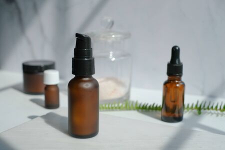 set of amber glass cosmetic skincare packaging . beauty product mock up on luxury white marble with natural light and shadow.の写真素材
