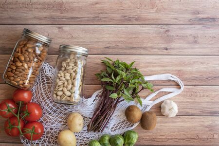 eco net bag of vegan health food on wooden background. plastic free grocery shopping. Top view. Flat layの写真素材