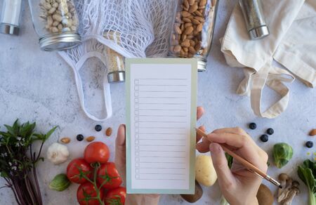 woman list on the note for vegan health food and zero waste lifestyle. plastic free grocery...