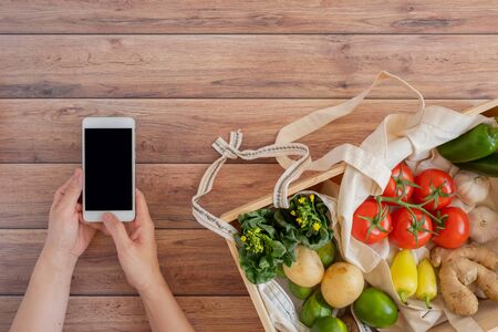 mobile phone with fresh vegetable in the wood box. online grocery and organic farmer product shopping application. food and cooking recipe or nutrition counting.flat lay.の写真素材