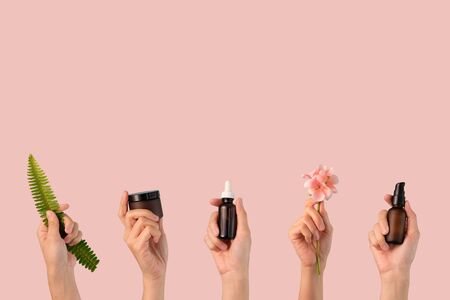 hand hold cosmetic skincare, flower, green leaf on pink background.beauty banner.の写真素材