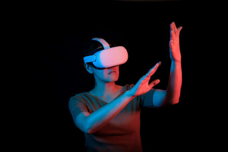 an adult woman is using VR headset to connect in the virtual reality and touch something like real. new futuristic technology concept.の写真素材