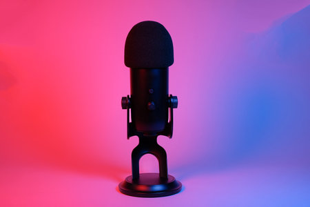 a black microphone on neon background under the neon light. podcasting, singing, and recording background.の写真素材