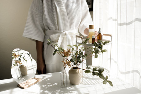The woman wearing a bathrobe pours oil on her skin. Skincare and spa concept. the beauty care and wellness lifestyle.の写真素材