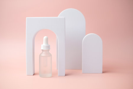 The white skincare dropper bottle is on pink background.の写真素材