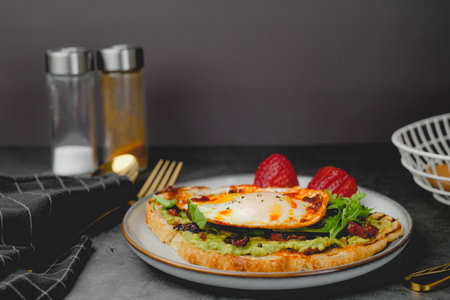 Healthy breakfast meal with sourdough, avocado, fried egg and strawberry. Mediterranean food and diet.の写真素材