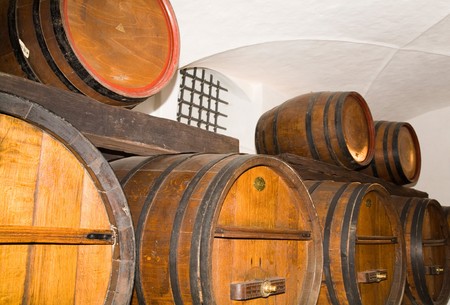 Wine ages in a cellar with traditional oak wine barrels