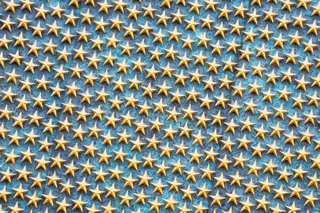 Closeup of golden stars in rows on a blue backgroundの写真素材