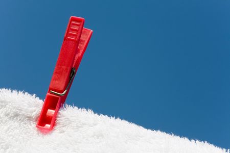 Clothes peg on a white towel and washing line against a blue skyの写真素材