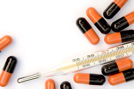 Thermometer and pills with copy space on a white background