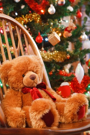Christmas interior with a teddy bear on a chair in front of a christmas treeの写真素材