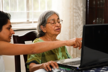 An Indian women shows her elderly mother how to use the internetの写真素材