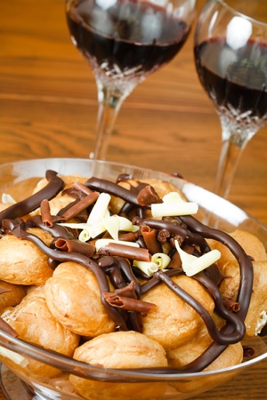 Bowl of profiteroles with glasses of red wine on a dining tableの写真素材