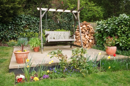 Relaxing garden patio with swing bench, potted plants and a wood pileの写真素材