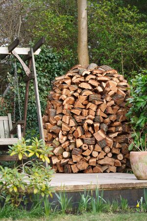 Circular wood stack or holz hausen with oak firewood seasoning in a gardenの写真素材