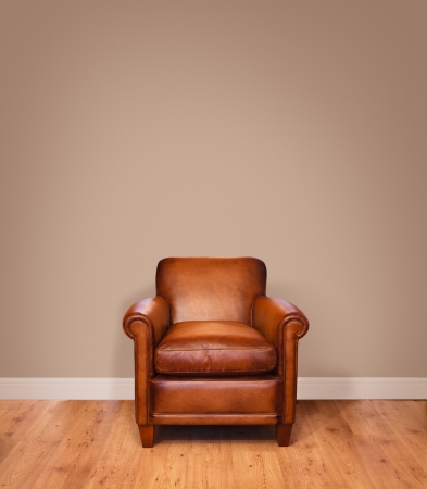 Leather armchair on a wooden floor against a plain background wall with lots of copyspace  The wall has a clipping path の写真素材