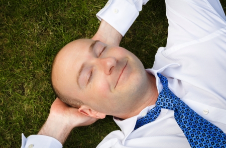 Closeup of an office worker resting lying on a grass lawnの写真素材