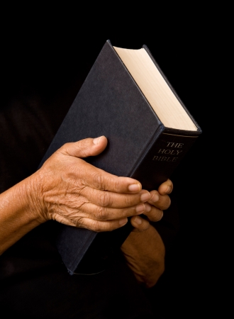 An old woman holds a bible in prayerの写真素材