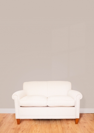 Modern cream sofa against a blank wall with lots of space for textの写真素材