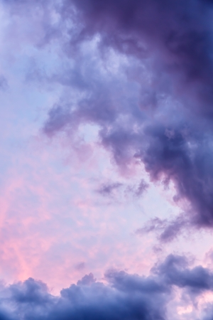 Dramatic dark storm clouds at sunset with hints of blue and redの写真素材