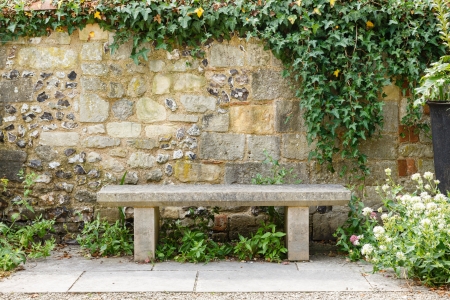 Bench in a formal garden with an old stone wallの写真素材