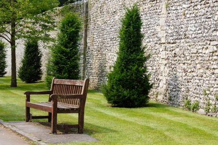 Wooden bench in a formal garden next to an ancient Roman wall in Winchester, UKの写真素材