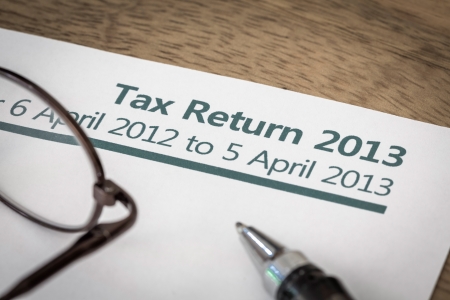 UK Income tax return form for 2013 on a desk with pen and glassesの写真素材