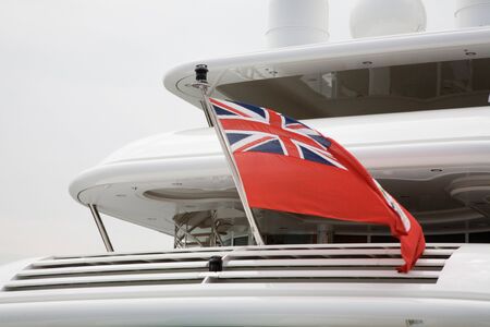 The British Red Ensign flag of the Royal Merchant Navy flies on the stern of a luxury yachtの写真素材
