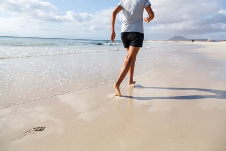 Asian Indian woman running on beach barefootの写真素材