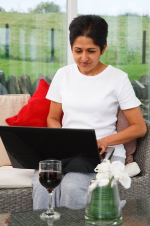 Young Indian Asian woman uses a laptop in a stylish homeの写真素材
