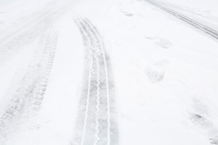 Closeup of tire tracks on a street with snowの写真素材