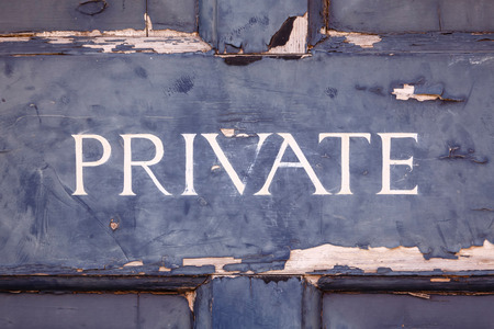 Closeup of a private sign on an old blue door with peeling paintの写真素材