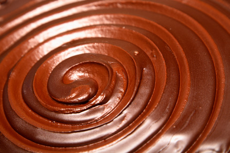 Detail of a swirl in chocolate icing on top of a rich chocolate cakeの写真素材