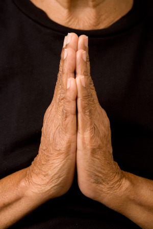 An old asian woman holds her hands in prayerの写真素材