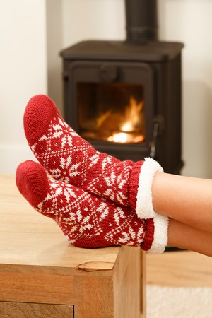 Woman warming feet in front of a cosy fire at Christmas timeの写真素材
