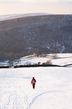 Woman walking in snow covered countryside, Peak District, UKの写真素材
