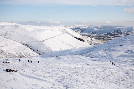 PEAK DISTRICT, UK - CIRCA 2012: A group of hikers walking up Kinder Scout in winter with Edale valley in the distance. Peak District, UKのeditorial素材