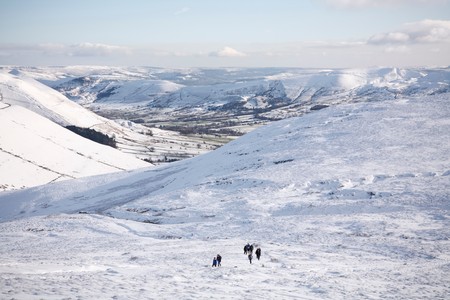 PEAK DISTRICT, UK - CIRCA 2012: A group of people hiking on Kinder Scout in winter with Edale valley in the distance. Peak District, UKのeditorial素材