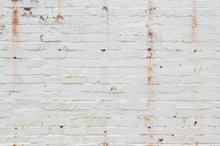 Detail of old brick wall painted white and distressed, peeling and stained. Ideal for grunge background textureの写真素材