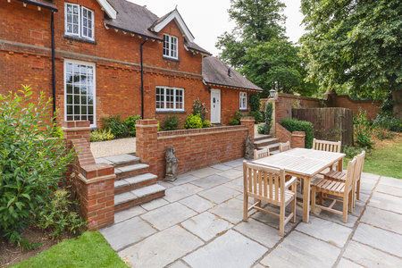 Large historic Victorian house featuring an English garden and patio with wooden furniture. Buckinghamshire, UKの写真素材