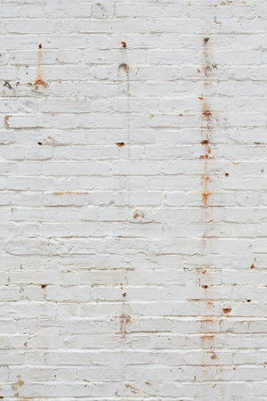 Detail of old brick wall painted white and distressed, peeling and stained. Ideal for grunge background textureの写真素材