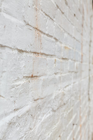 Detail of old brick wall painted white and distressed, peeling and stained. Ideal for grunge background textureの写真素材