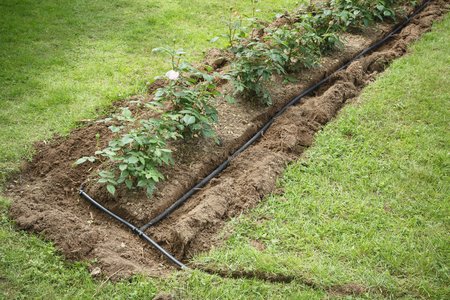 Soaker hoses installed in trenches for water irrigation to a garden flower bedの写真素材