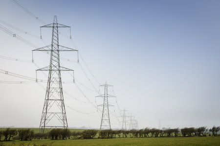 A line of electricity pylons in UK countryside. With blue sky and copy spaceの写真素材