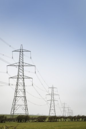 A line of electricity pylons carries power cables across open countryside. With copy spaceの写真素材