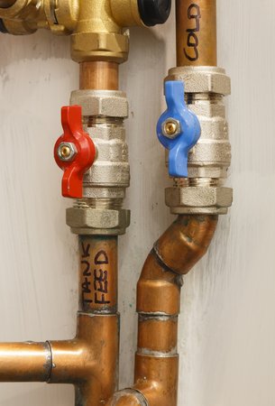 Hot and cold copper water pipes with isolation valves. Depicts plumbing and water supplyの写真素材