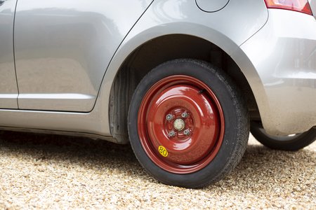 Space saver wheel and spare tyre or tire fitted to a small carの写真素材