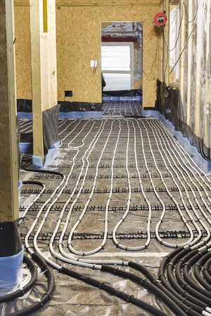 Underfloor heating water pipes installation to subfloor of a house under constructionの写真素材
